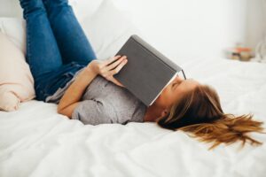 Kvinde læser bog oven på sin seng