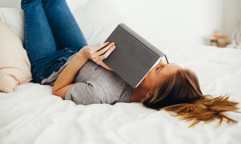 Kvinde læser bog oven på sin seng